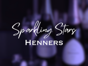 Text: Sparkling Stars. Henners. With a blurred background of bottles of wine.