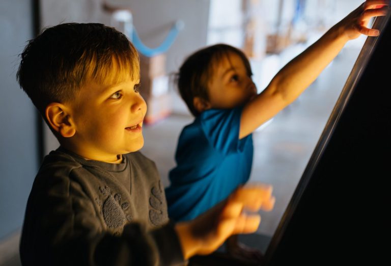 A boy wearing a green top is inside an amazing playground construction that has swooping metal bars and round balls representing planets