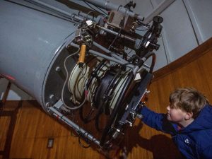 Boy looking through an historic telescope