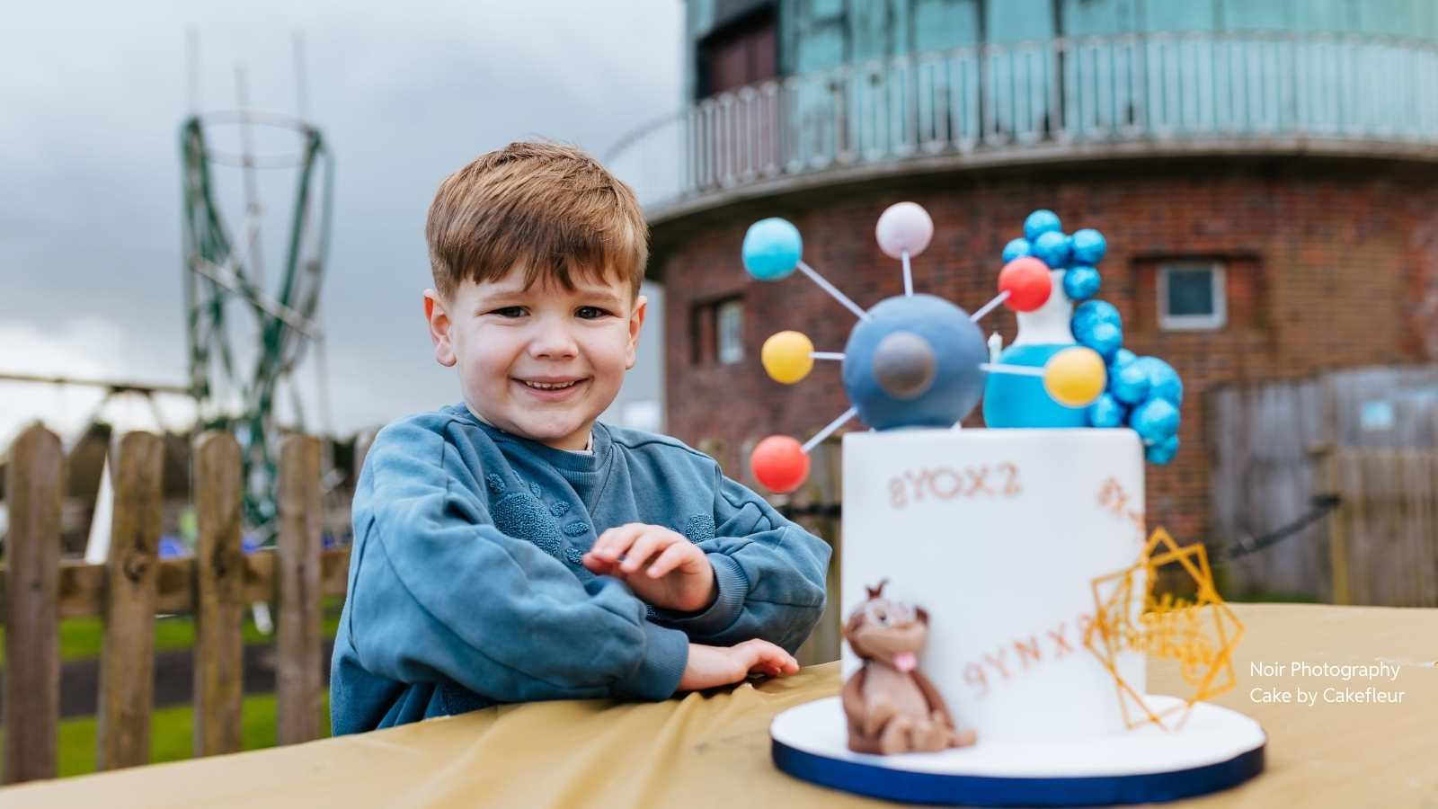 birthday Boy with birthday cake in front of telescope dome