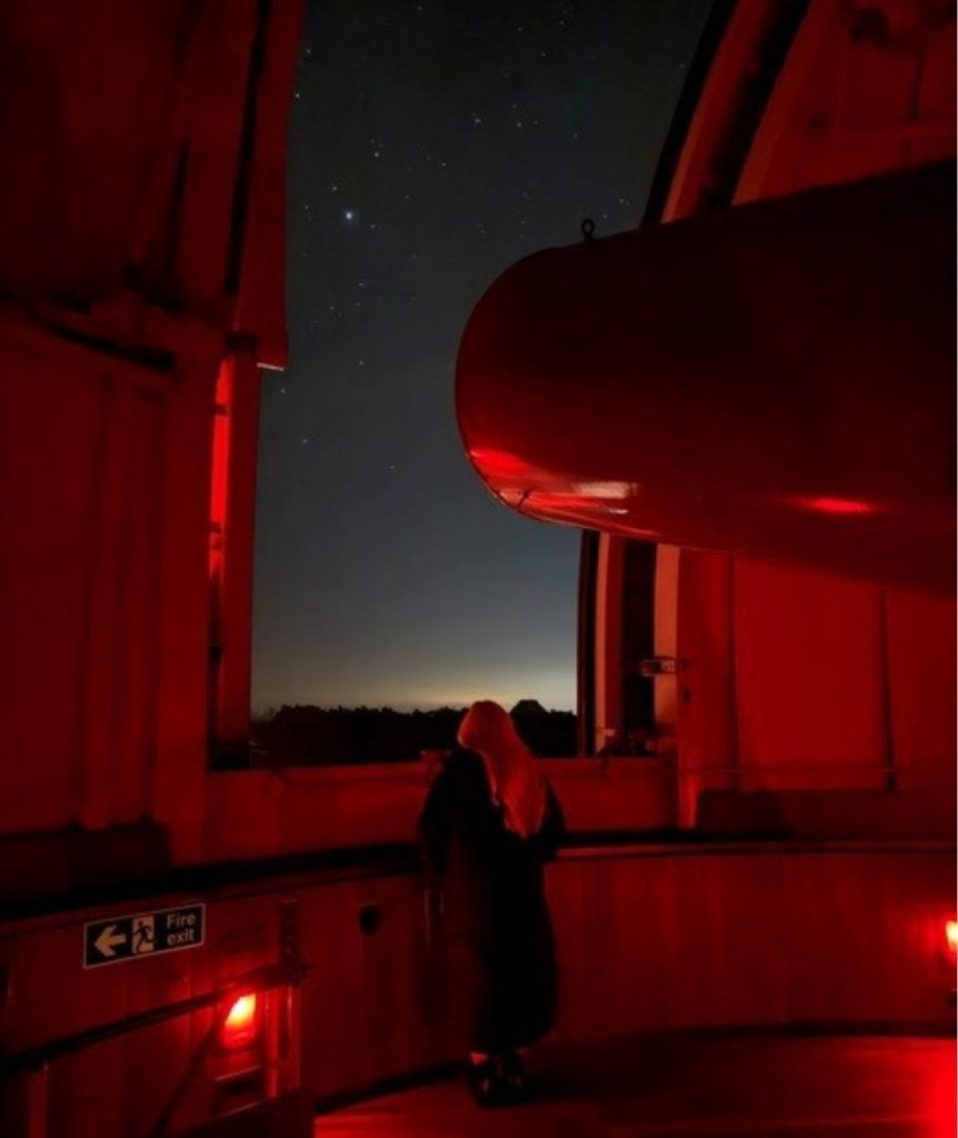 Woman inside telescope dome viewing the night sky