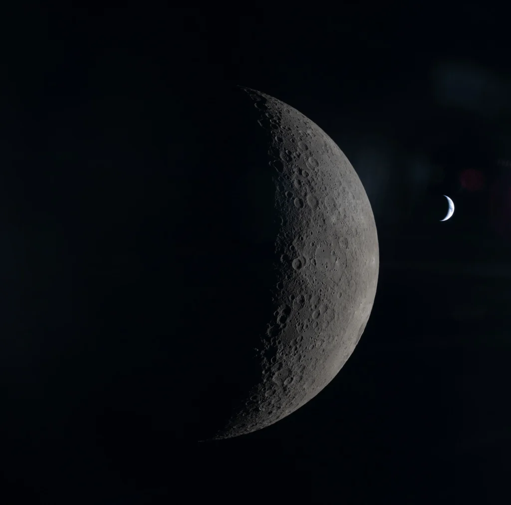 The Moon in the foreground with a crescent Earth in the background